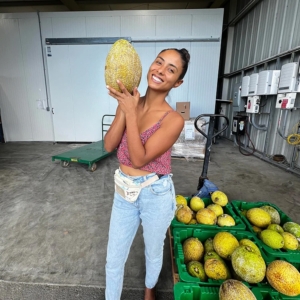 Our friend Anissa in the warehouse holding up a breadfruit from the pallets.