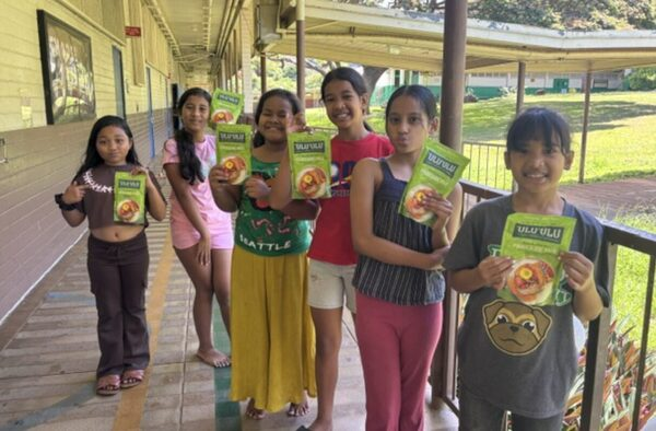 Students holding Hoʻopili ʻAi educational boxes outside their classroom
